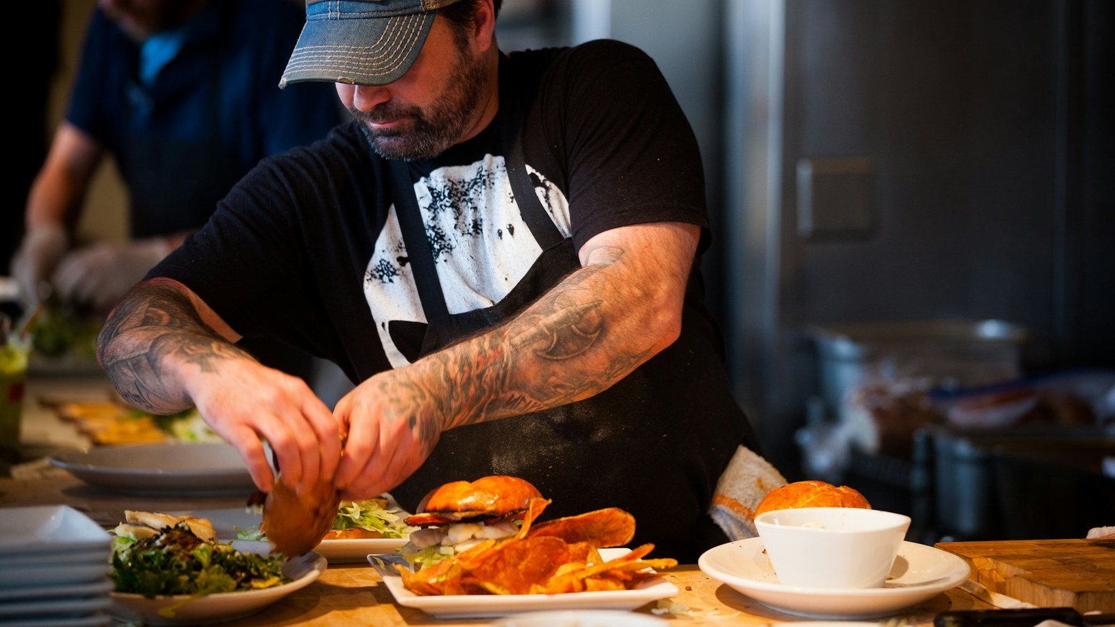 A cook plating a dish in a busy restaurant kitchen